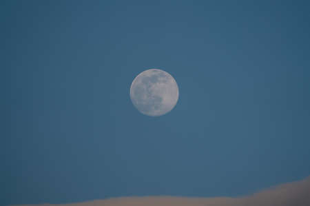 A big moon with some clouds and blue sky at the afternoon