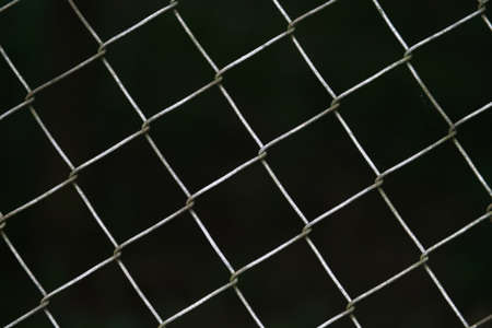A wire mesh fence with dark background