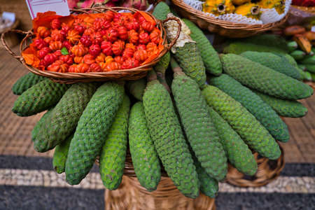 Monstera fruit or bananas, Monstera deliciosa, with a besaket pitangas on it on a market in Funchal,...