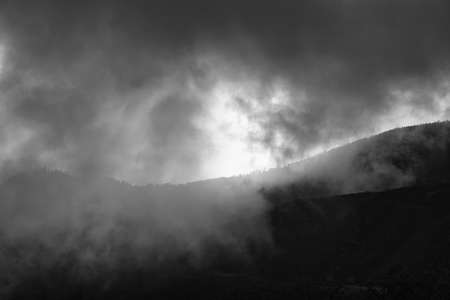 a black and white picture taken from the mountain down through the clouds to the shining atlantic...