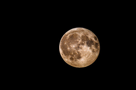 Close-up of the full Moon (Luna) showing sharp crater details and warm surface tones. Captured in...