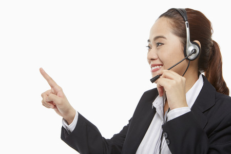Businesswoman with headset pointing to the rightの写真素材