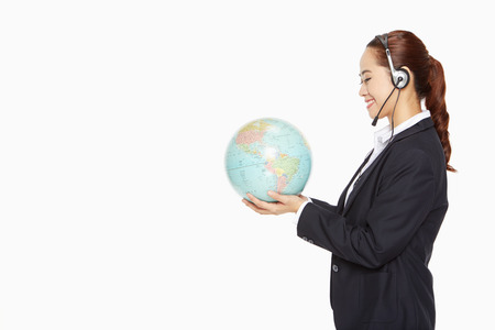 Businesswoman with headset holding a globeの写真素材
