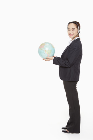 Businesswoman with headset holding a globeの写真素材