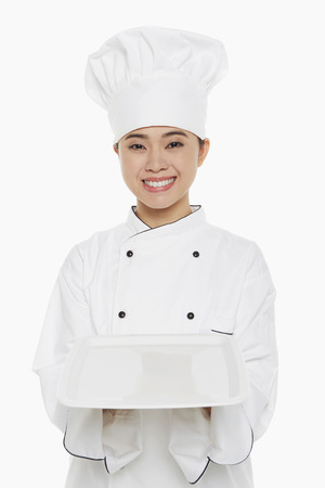 Female chef holding up a trayの写真素材