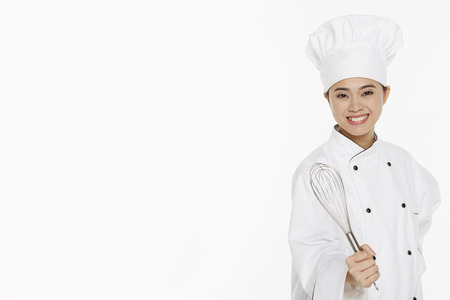 Female chef holding a wire whiskの写真素材