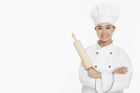 Female chef holding up a rolling pinの写真素材