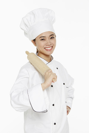 Female chef holding up a rolling pinの写真素材
