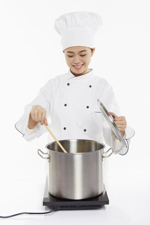Female chef cooking and stirringの写真素材
