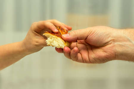 Two hands, pass a piece of bread, the background is blurredの写真素材