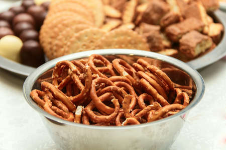 savoury straws in the iron bowl, in the background a variety of biscuits, chocolate, biscuit dough