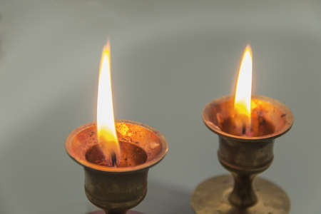 two burning candles on a gray background, photographed close upの写真素材