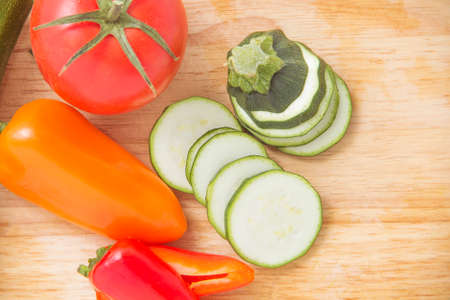 zucchini to cut circles, red tomato, pepper red and yellow, on a wooden boardの写真素材