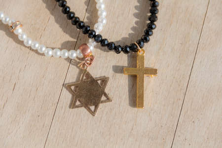 Two pearl necklaces, one with the cross, another star of david with the star-six-corners, on wooden backgroundの写真素材
