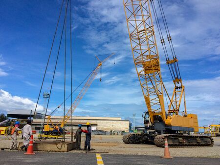 workers hooking up sling lifting a larger cement platform by crane in the work areaのeditorial素材
