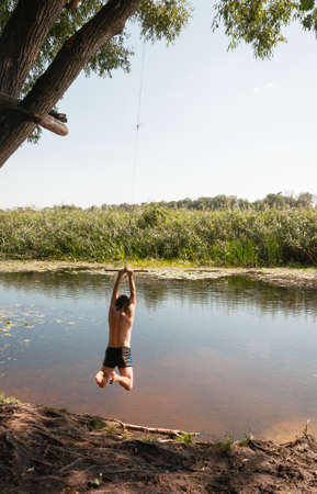 A young man jumping with bungee into the river. Quality image for your projectの写真素材