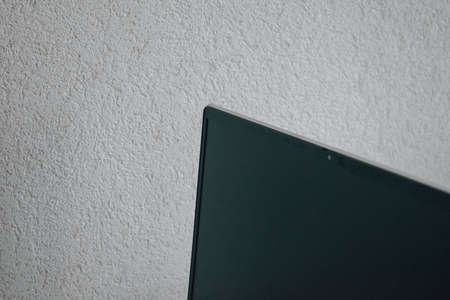 Black laptop screen on a white wall background. Space for inscription. Quality image for your...