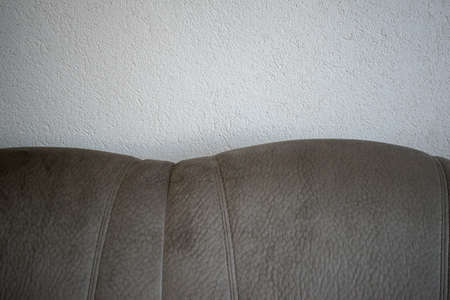 Gray soft sofa on a white wall background. Minimalist interior. Space for inscription. Quality image...