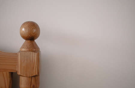 Decorative carved back of a wooden bed on the background of a white plastered wall. Space for inscription. Quality image for your projectの写真素材
