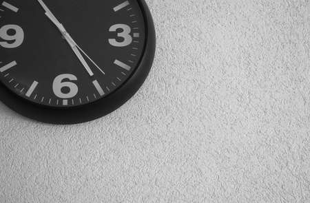 Round clock with arrows on a white wall. Space for inscription. Quality image for your project