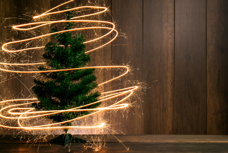abstract Symbolic Christmas tree created using sparklers with wood table and wood wall background happy new year concept.の写真素材