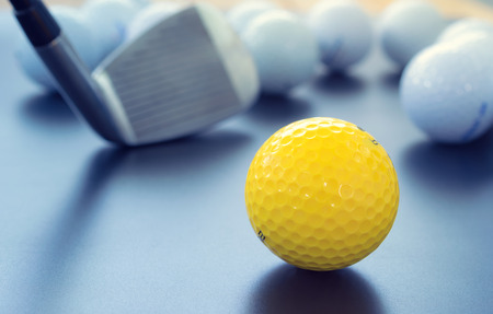 white and one yellow golf balls on black floor. individuality and difference concept.の写真素材