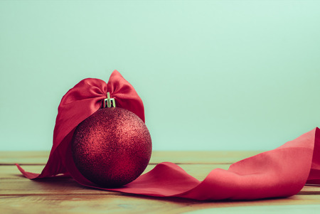 red Christmas ball with ribbon on wood table and copy space background.の写真素材