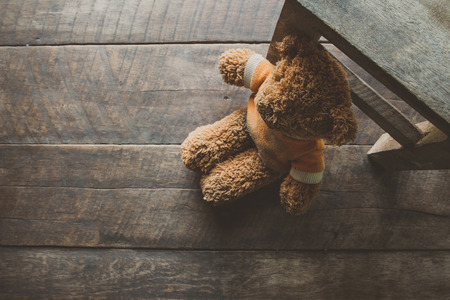 old Teddy Bear alone on wooden floorの写真素材