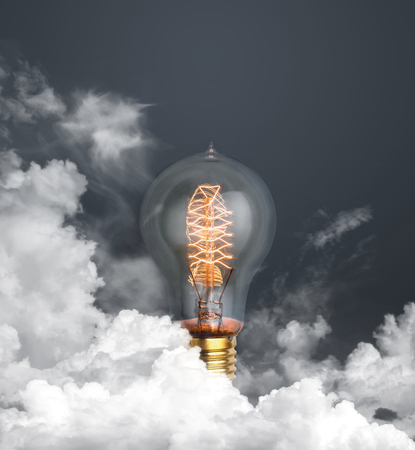 abstract light bulb glowing on dark grey background with clouds alternative technology concept.の写真素材