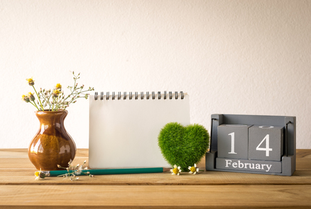 vintage wood calendar for February 14 with green heart, notebook,pencil on wood table love and valentine's day concept background, backdrop.の写真素材