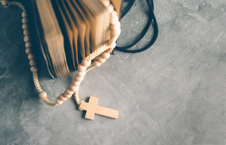 Catholic rosary beads with old book on cement table prayer, rosary background concept in vintage...