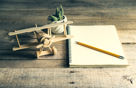 wood toy airplane with blank notebook and pencil on wood table .の写真素材