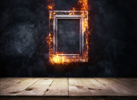 Fire Burning silver Antique picture Frame on dark grunge wall with Wooden table top, Empty ready for product display or montage.の写真素材