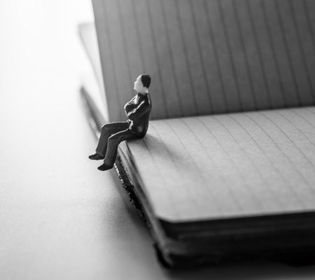 thinking man, miniature man sitting alone on notebook.の写真素材