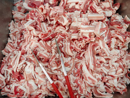 A large metal container filled with freshly cut pork belly pieces ready for culinary use. Ideal for various cooking methods and dishes.の写真素材