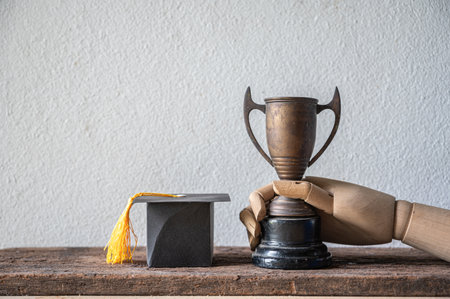 This image depicts a graduation trophy alongside a classic cap, symbolizing achievement and success in education. Perfect for celebrating milestones.の写真素材