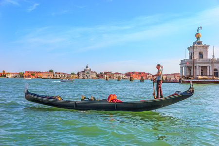 Venice/Italy - August 22, 2018: A gondolier in the lagoon passing Art Museum Punta della Doganaのeditorial素材
