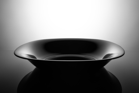 Empty black soup plate, isolated in the shadowsの写真素材