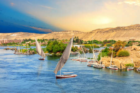 Sailboats in front of the hills of the Nile in Aswan, Egypt.の写真素材