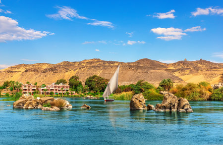 Nile stones and riverbank near Aswan and traditional sailboat, Upper Egypt.の写真素材