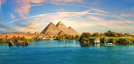 Lonely Saleboat in the Nile river and ancient rocks in the Aswan desert by the pyramids, Egypt.