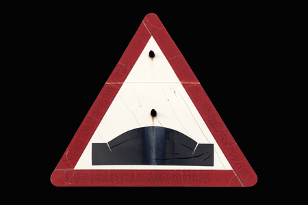 Old dirty rusty triangular red border road sign 'Hump' isolated on black.の写真素材