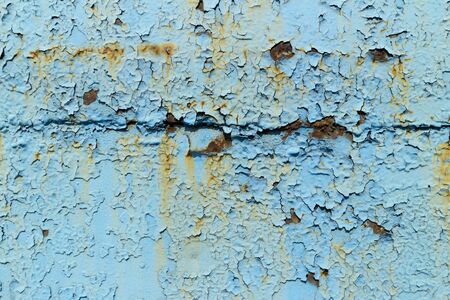 Rusty metal surface painted with peeling blue paint.