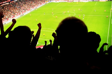 Silhouettes of fans celebrating a goal on football matchの写真素材