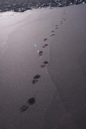 Man's barefeet in black sand in Maui, Hawaii.の写真素材