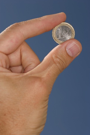 one euro in hand between fingersの写真素材
