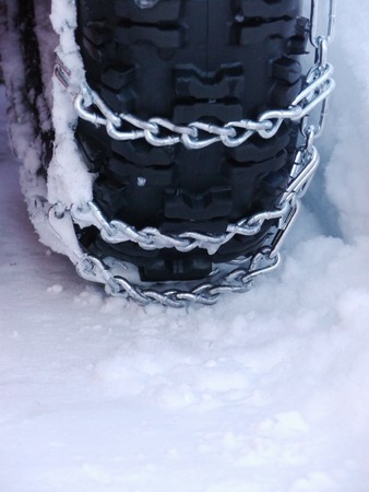 Snow chains outside at a wheel in winterの写真素材