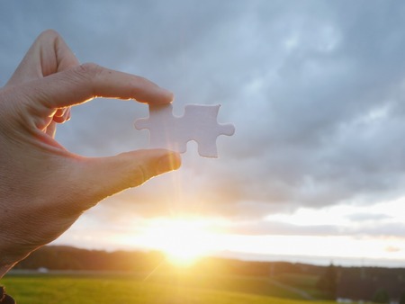 Pinch a piece of the jigsaw puzzleの写真素材