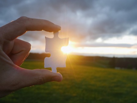 Pinch a piece of the jigsaw puzzleの写真素材