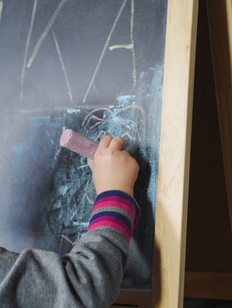kids hand holding a white chalk about to writeの写真素材